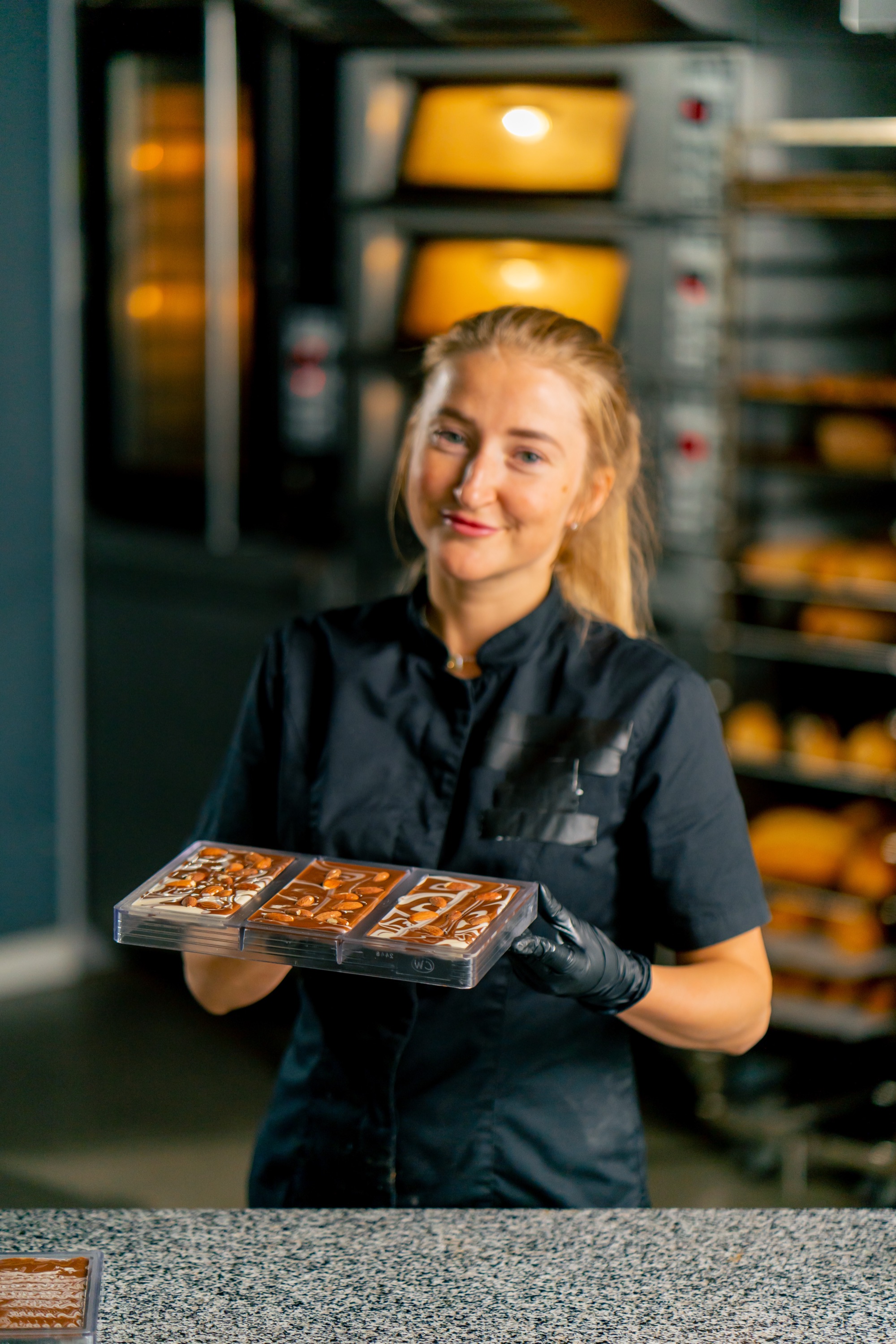 Konditorin hält ein Blech mit Pralinen