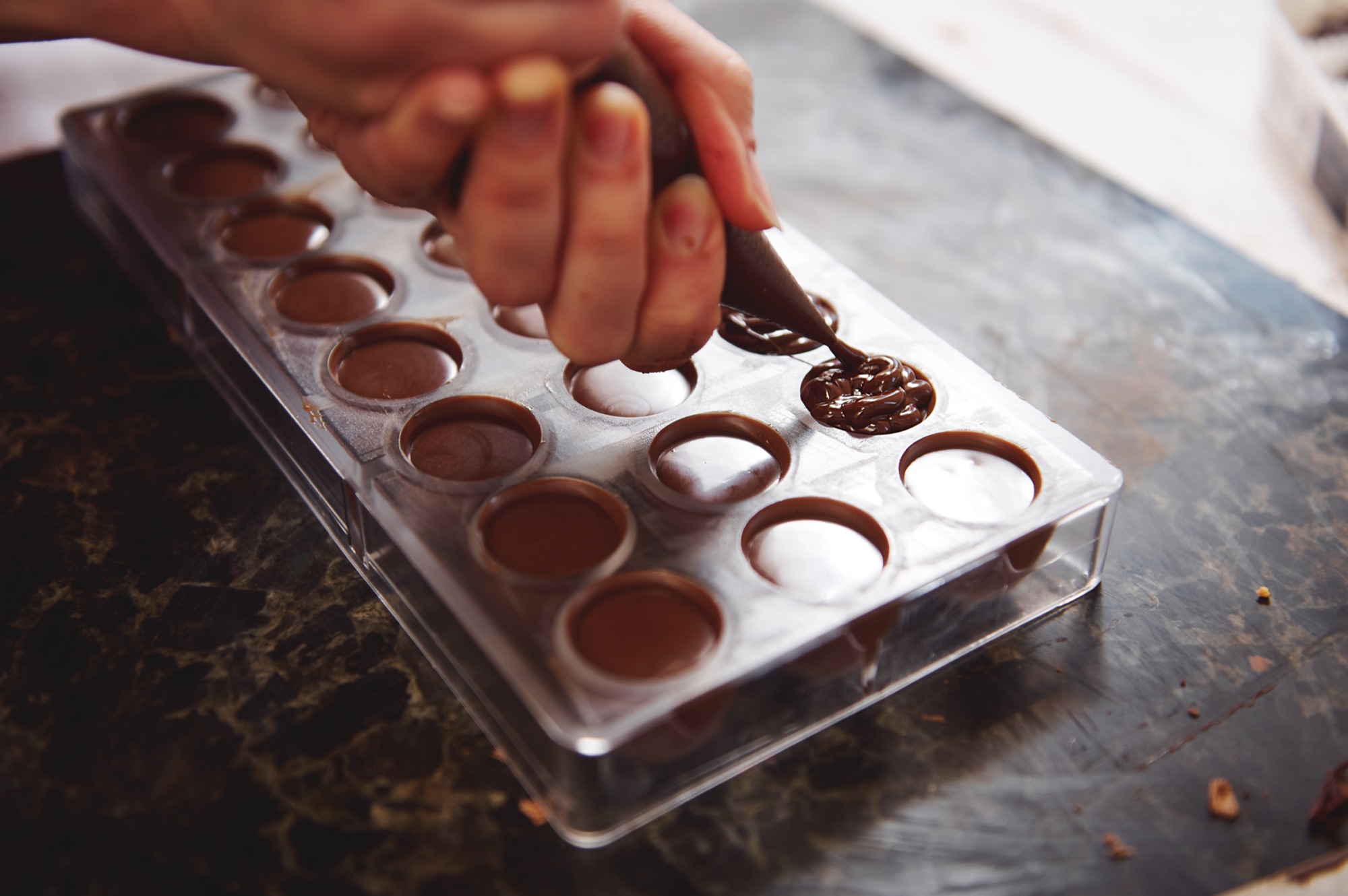 Pralinenform wird mit Schokolade gefüllt